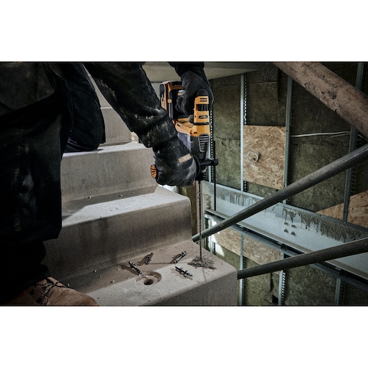 Person drilling concrete stairs with a DEWALT tool at a construction site. Several screws are placed nearby.