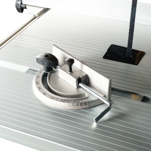 Close-up of a metal miter gauge and cutting surface on a DEWALT band saw.