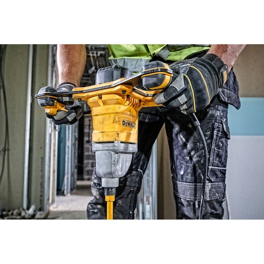 Person operating a DEWALT DWD241 mixer drill on a construction site, wearing gloves and workwear.