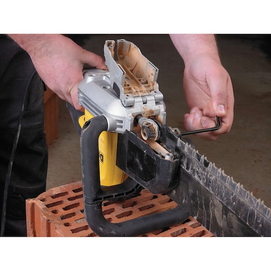 Person using a hex key to adjust a DEWALT electric masonry saw placed on a brick.