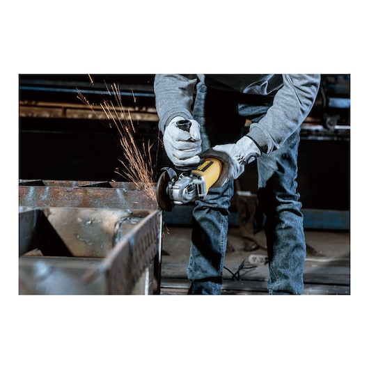 A person wearing gloves uses a yellow DEWALT angle grinder to grind a metal surface, producing sparks.