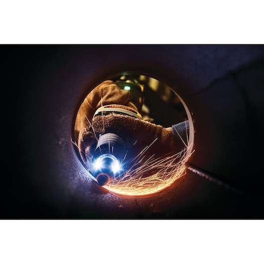 Close-up of DEWALT grinder creating sparks inside a metal pipe during industrial work.