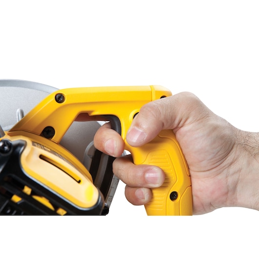Hand gripping the yellow handle of a DEWALT power tool, close-up view of the trigger and tool details.