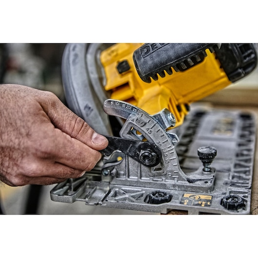 Hand adjusts angle setting on a yellow DEWALT circular saw for precise woodworking.