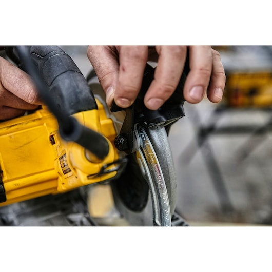 Hand adjusting the depth setting on a yellow DEWALT circular saw.