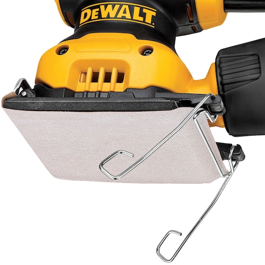 Close-up image of a DEWALT DWE6411 electric hand sander, showing the yellow body, black handle, and the attached sandpaper secured by metal clips.