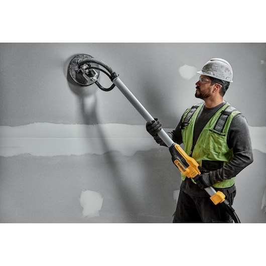Worker uses DEWALT DWE7800, DWE7800-QS wall sander on drywall. Photography product shown in action.