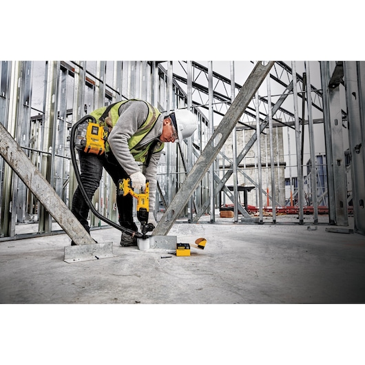 Worker uses DEWALT DWH161D1 cordless extraction system on a construction site with metal framing.