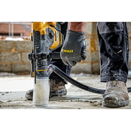 DEWALT dust extractor attached to a power tool in use on a concrete floor at a construction site.