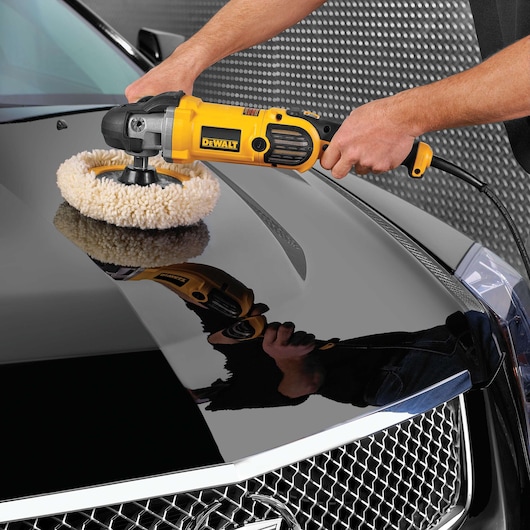 DEWALT polisher in use on a shiny car hood, demonstrating automotive detailing and surface polishing.