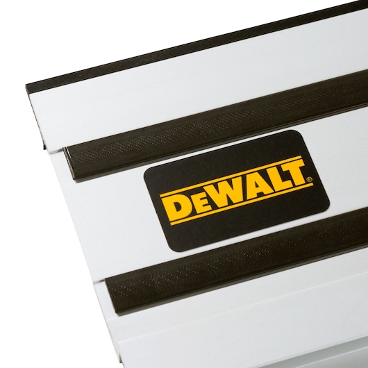 Close-up of a DEWALT branded silver metal guide rail with black strips, used for photography or cutting tasks.