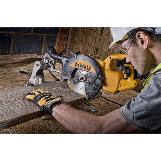 A DEWALT DWS773 saw is used to cut wood. Person wearing gloves and safety gear operates on a construction site.