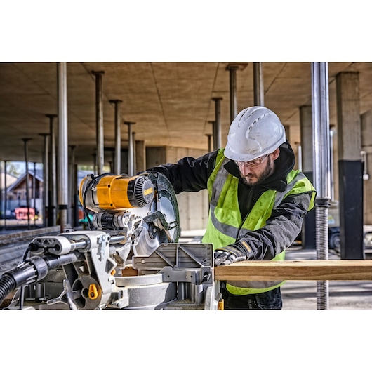 DEWALT DWS780, DWS780KIT miter saw used by worker cutting wood at construction site. Photography category.