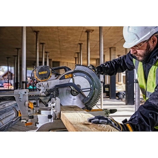 DEWALT DWS780, DWS780KIT miter saw in use at a building site. Worker cuts wood. Photography product category.