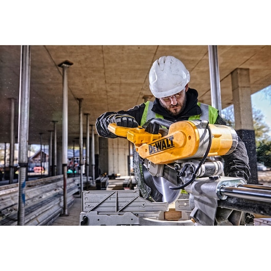 DEWALT DWS780, DWS780KIT saw in use at construction site, worker with helmet and vest. Photography category.