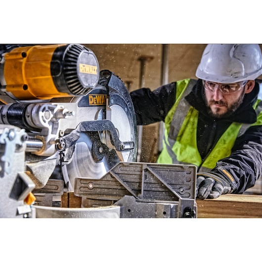 DEWALT DWS780, DWS780KIT saw in use at construction site. Worker in safety gear. Photography product category.