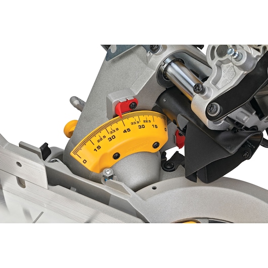 Close-up view of a DEWALT miter saw adjustment gauge, featuring a yellow measurement scale for angle settings and metal construction.