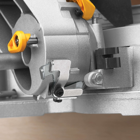 Close-up view of a metallic component on a DEWALT power tool, featuring adjustment knobs and locks, likely part of a mitre saw mechanism.