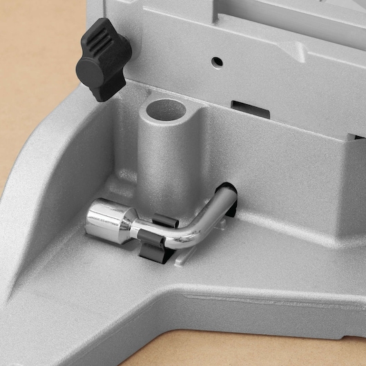 Close-up of a metallic component of a DEWALT machine, showing a silver L-shaped metal rod attached to a gray base, with a black knob above.