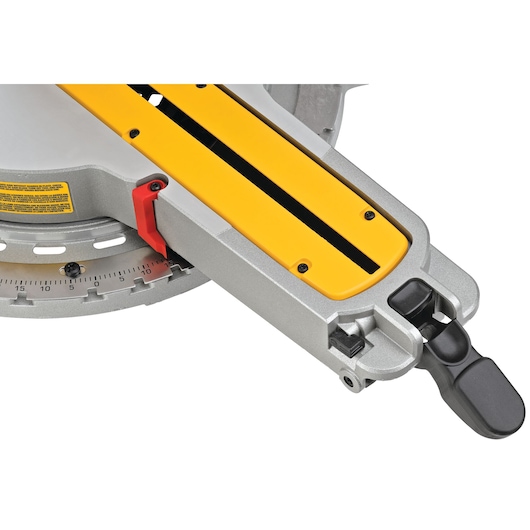 Close-up view of a DEWALT DWS780 miter saw base, showing the yellow and silver sliding arm, angle adjustment scale, red lever, and black locking handle.
