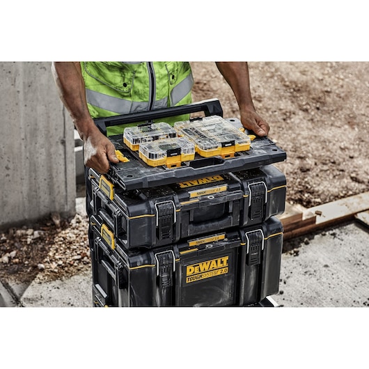 DEWALT ToughSystem 2.0 boxes on site, SKUs DWST08017, DWST08017-1, DWST08017-9 stacked and carried by worker.