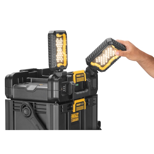 A DEWALT ToughSystem 2.0 storage box with two mounted LED work lights, one being adjusted by a hand.