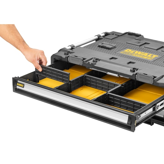 DEWALT organizer box with multiple compartments and a hand adjusting the divider in a pull-out drawer.