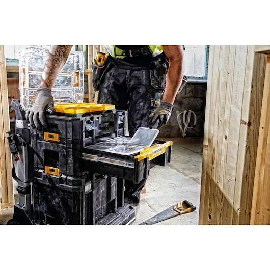 Worker uses DEWALT DWST1-70705 stackable tool storage with sliding drawer at construction site.