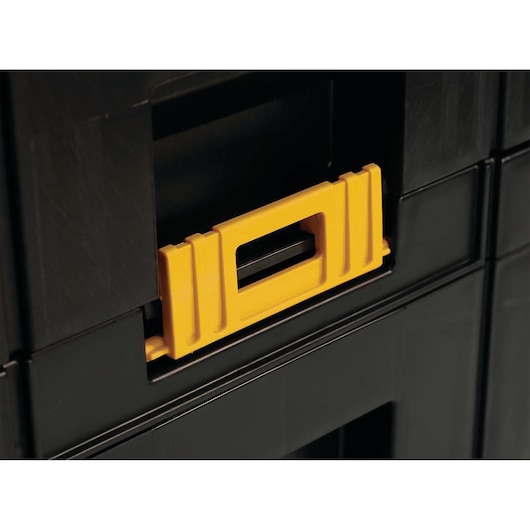 Close-up of a DEWALT black storage box with a yellow latch for secure stacking.