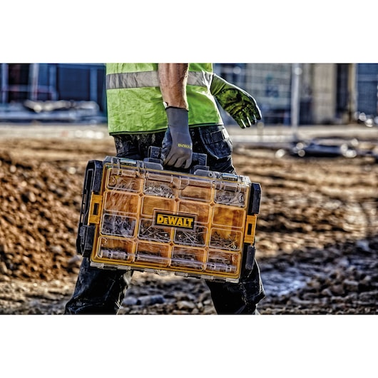 Worker carries DEWALT organizer with compartments on a construction site.