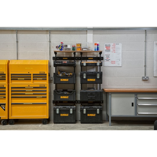 DEWALT toolboxes and storage units organized in a workshop next to a workbench and yellow tool cabinets.