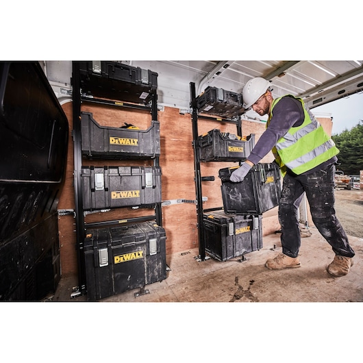 Person stores DEWALT tool boxes on van racks. Tool boxes are organized for secure transport and easy access.