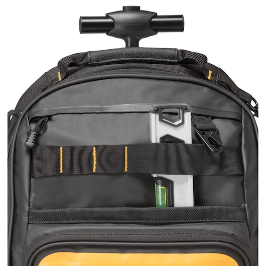 Close-up of a DEWALT black and yellow rolling tool bag showing the telescopic handle, a front pocket, and a spirit level stored behind a black strap.