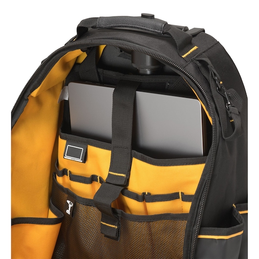Close-up view of the inside of a DEWALT backpack, showing yellow compartments and pockets holding a laptop and various items.