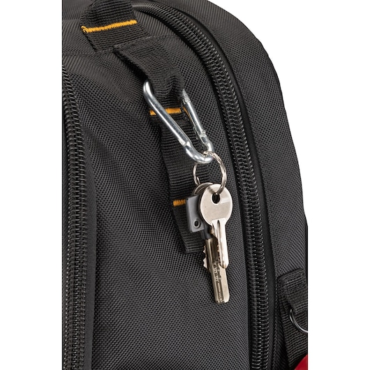 Close-up of a black fabric bag with a carabiner clip attached to a strap, holding a keyring with two keys.