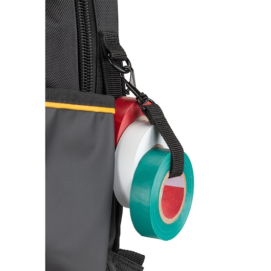 Close-up of three rolls of colored adhesive tape attached to a black strap and hook on the side of a grey bag with a yellow trim.