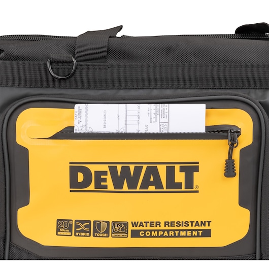 Close-up of a DEWALT black and yellow bag featuring a front compartment with a zipper, containing a rolled technical document. The compartment is labeled 'WATER RESISTANT COMPARTMENT' along with icons for size, hybrid use, toughness, and IP54 rating.