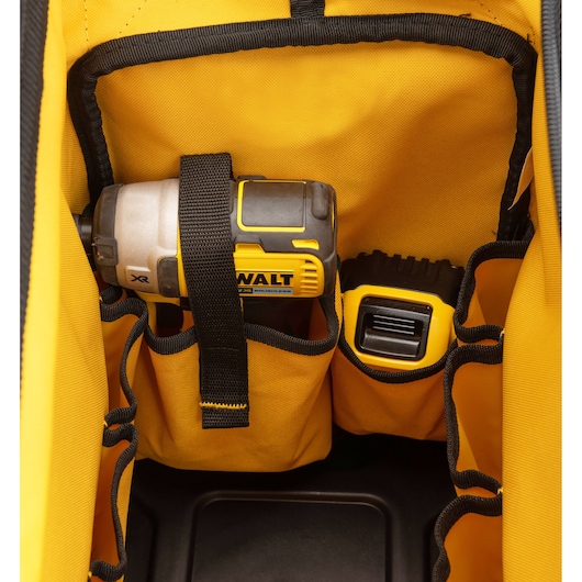 Close-up of a yellow DEWALT tool bag showing internal pockets holding a DEWALT power tool and accessories.