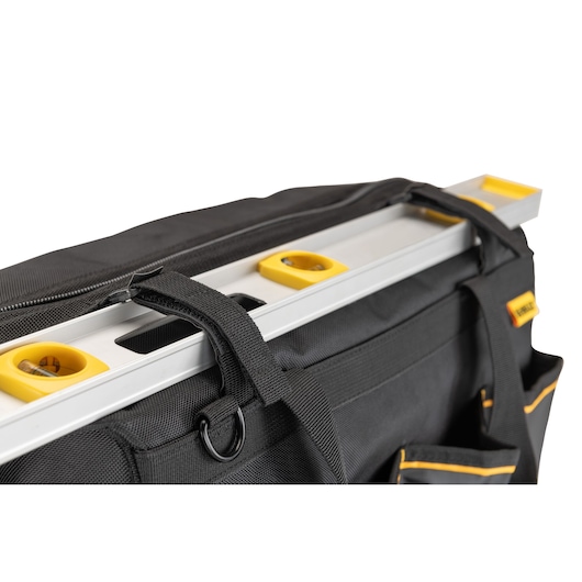 Close-up of a DEWALT black tool bag with yellow-edged pockets, featuring a silver and yellow spirit level secured in an external strap holder.