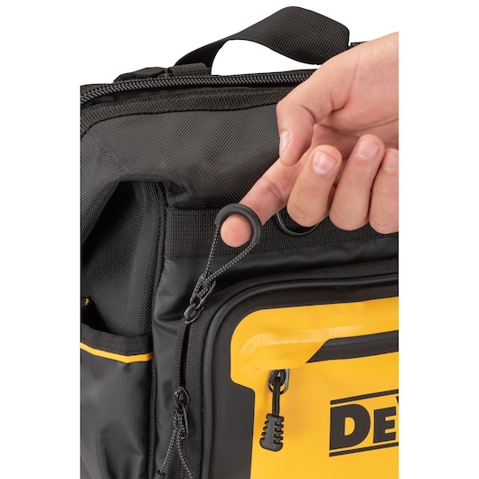 Close-up of a hand opening a zipper on a DEWALT tool bag, showing the yellow and black design.