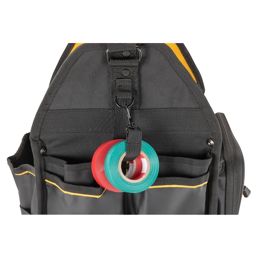Close-up view of a DEWALT black tool bag with two rolls of tape, one red and one green, attached to a loop on the front.
