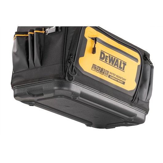 Close-up of a DEWALT tool bag with a hard plastic base, multiple side pockets, and a yellow front zipper pocket labeled 'Water Resistant Compartment.'