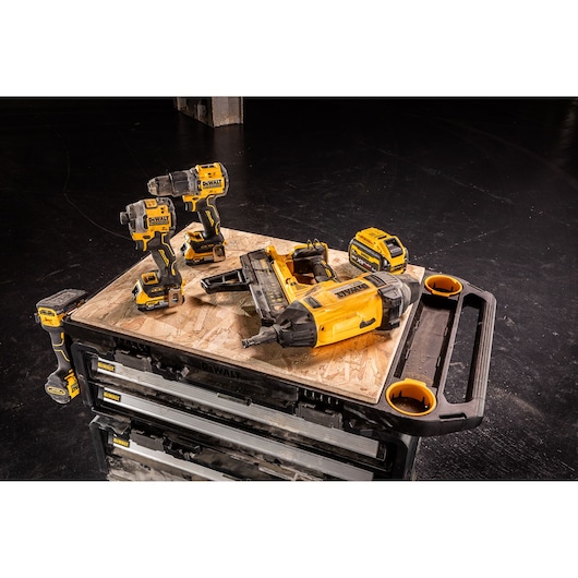 DEWALT power tools and battery charger set on a workbench with a black background.