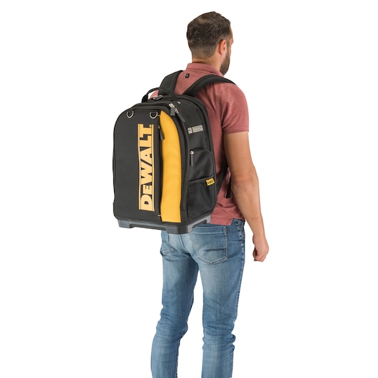 Person wearing a DEWALT black and yellow backpack, viewed from the back against a white background.