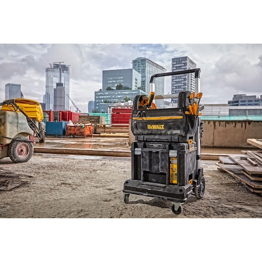 DEWALT mobile tool storage cart on a construction site with city buildings in the background.