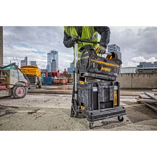 DEWALT tool storage system on wheels used at a construction site with city buildings visible in the background.