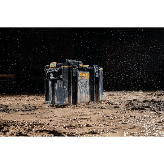 DEWALT DWST83342-1 tool box shown in muddy conditions with water splashing, highlighting durability.