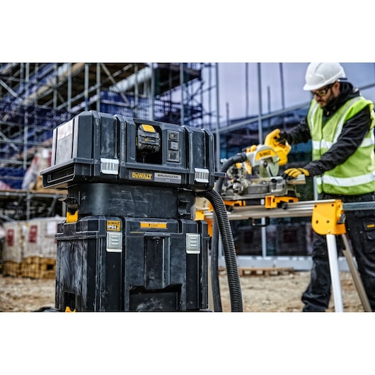 DEWALT tool storage and vacuum system on a construction site, worker using power tool in background.