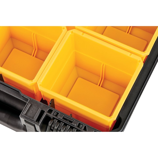 Close-up of yellow plastic compartments in a black DEWALT storage box.