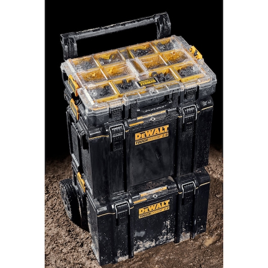 Stacked DEWALT ToughSystem 2.0 toolboxes with wheels and organizer, covered in mud, shown on a dirt surface.